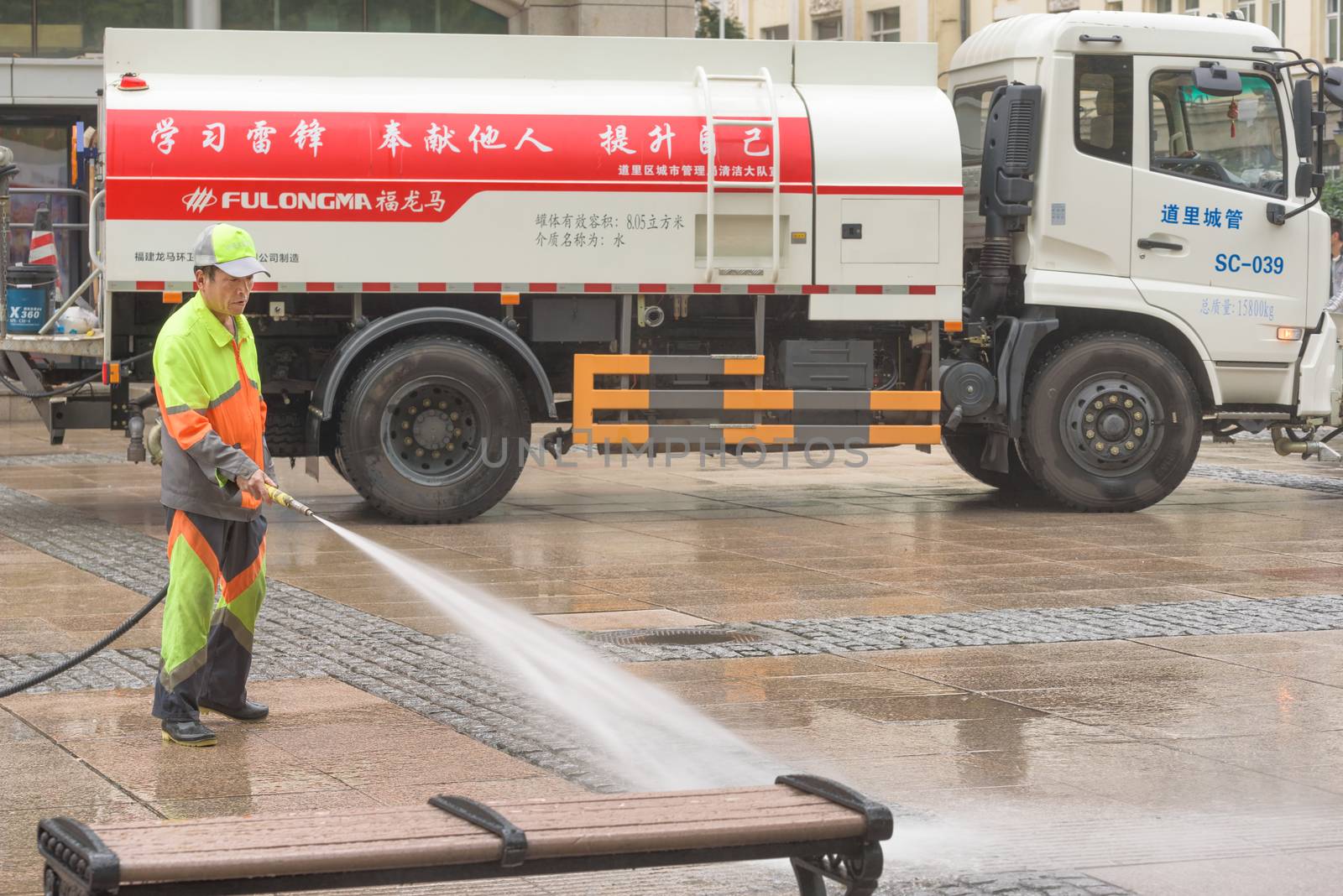 Harbin, Heilongjiang, China - September 2018: Man washes the pavement. Worker cleaning the street