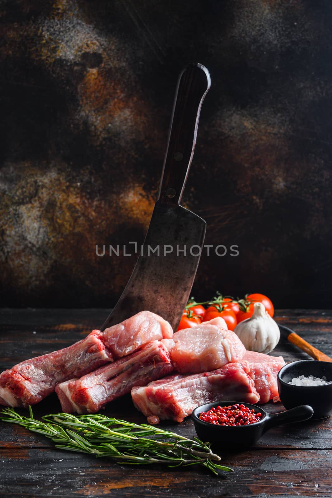 Fresh raw pork meat from organic farm with spices: pepper, salt, bay leaf. Butcher chopping cleaver in wood table over rustic wood and metal Food background side view .