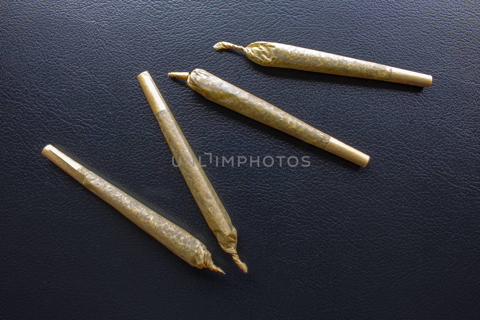 Cannabis Pre-Roll Joints Cigarettes on a leather black texture. by oasisamuel