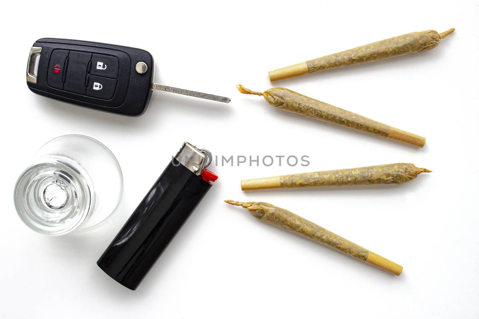 Cannabis Joints Cigarettes with car key, a shoot glass and a lighter on a white background. Concept driving high. Drug-impaired driving is dangerous and against the law by oasisamuel