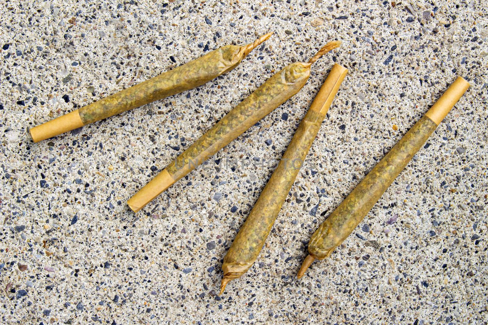 Cannabis Pre-Roll Joints Cigarettes on a concrete texture.