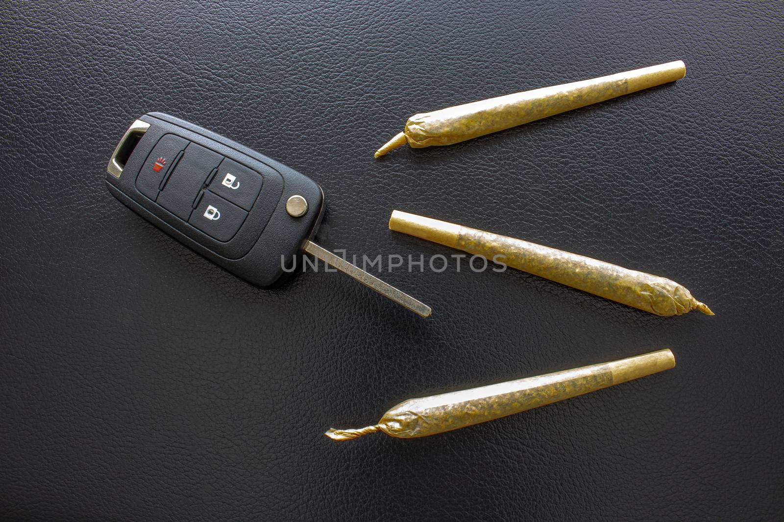 Cannabis Joints Cigarettes with car key on the side on a leather black texture. Concept driving high. Drug-impaired driving is dangerous and against the law