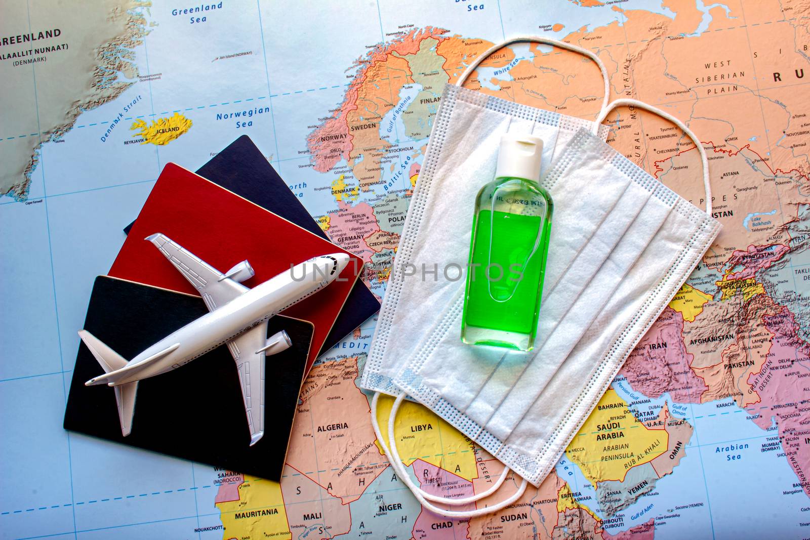 Passports with a plane and face mask and hand sanitizer on a world map. Concept traveling on a place during a global pandemic. Trave durin covid 19.l