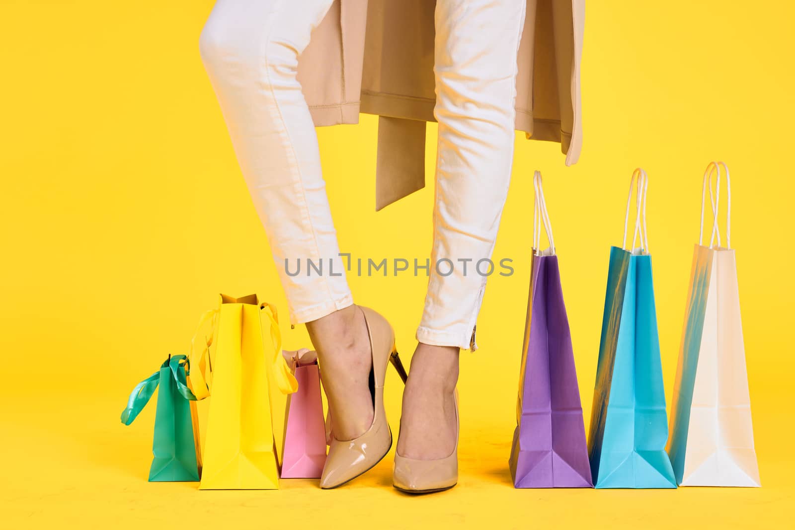 female feet in shoes packs shopping lifestyle yellow isolated background by SHOTPRIME