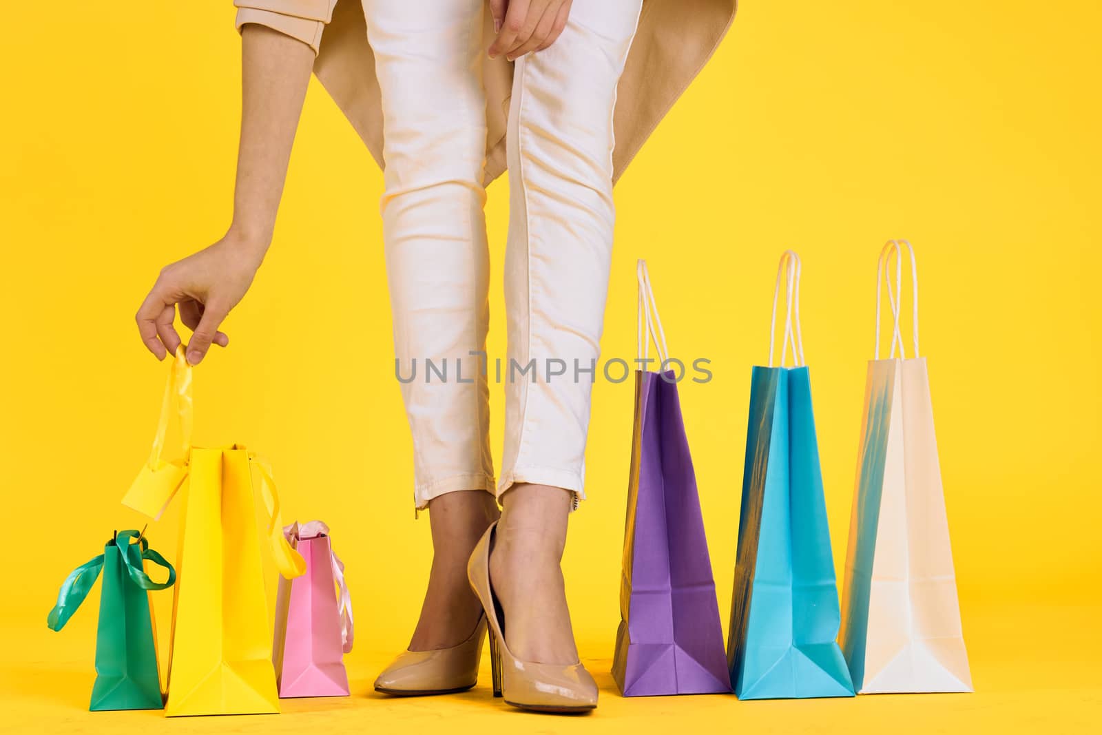 female feet in shoes packs shopping lifestyle yellow isolated background. High quality photo