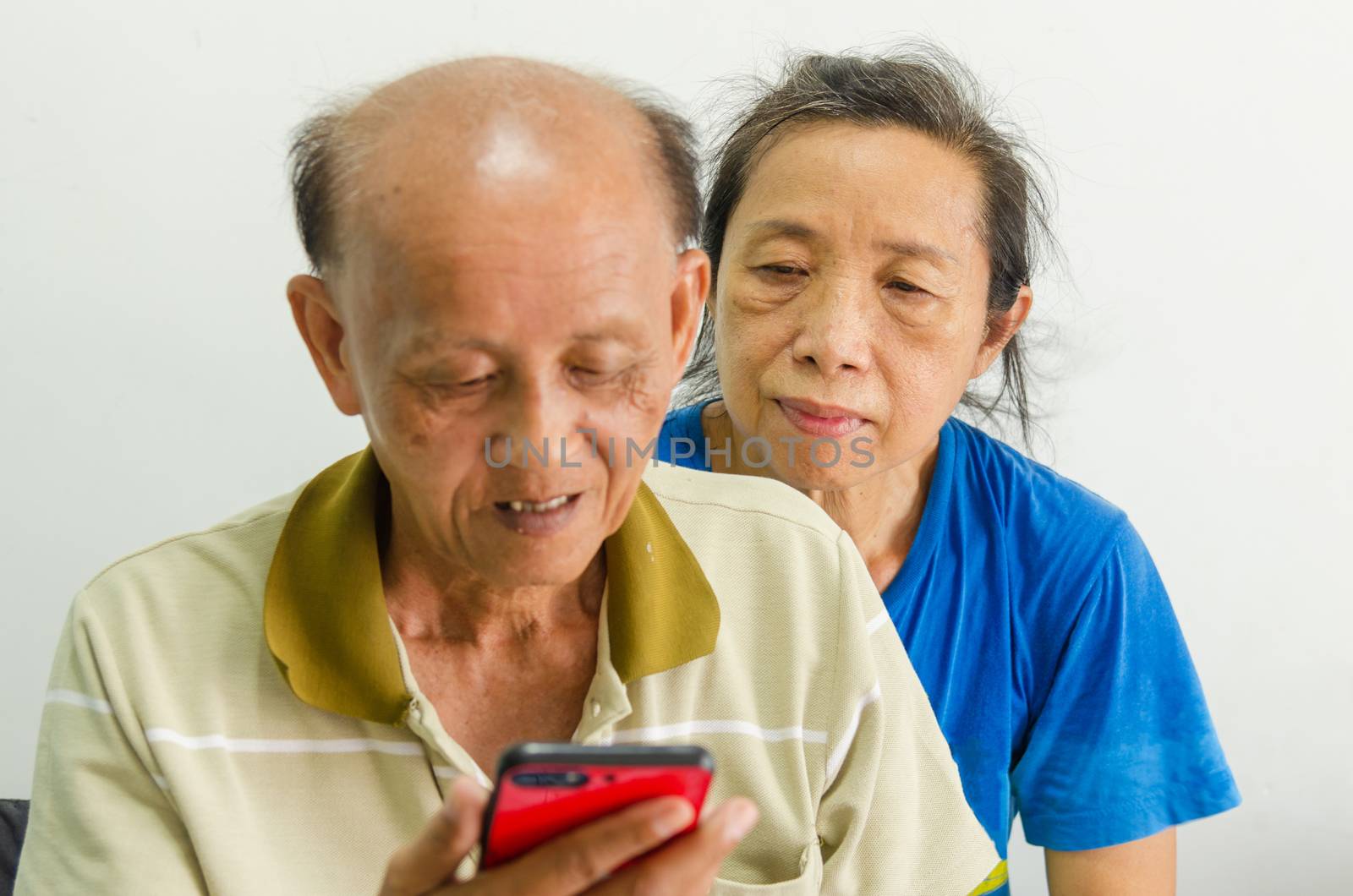 Older Asian women and men look at mobile phones by aoo3771