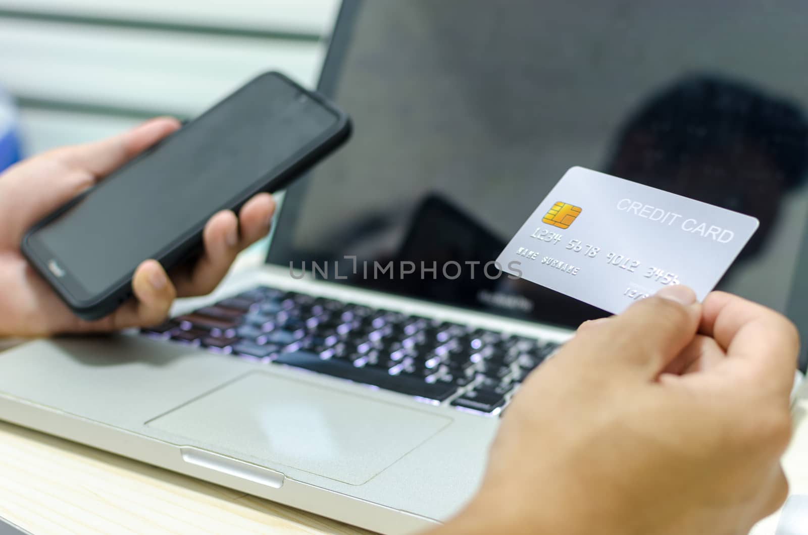 Man Shopping Online Using Laptop With Credit Card.Hands holding credit card and smartphone.