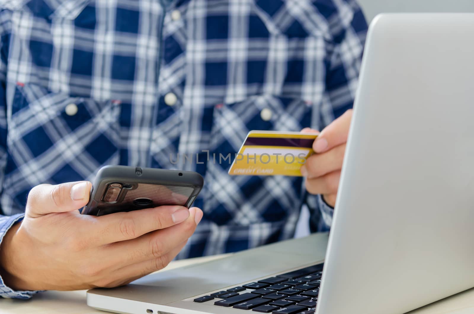 Man Shopping Online Using Laptop With Credit Card.Hands holding credit card and smartphone.