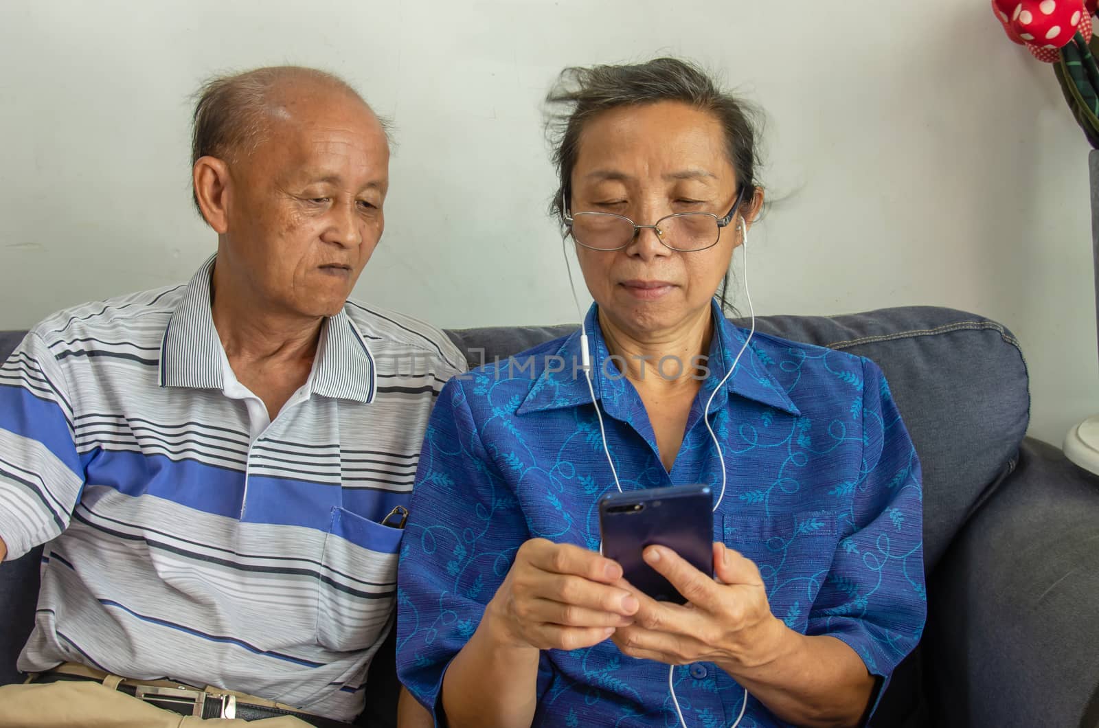 Portrait of a senior Asian couple using a mobile phone to listen to music