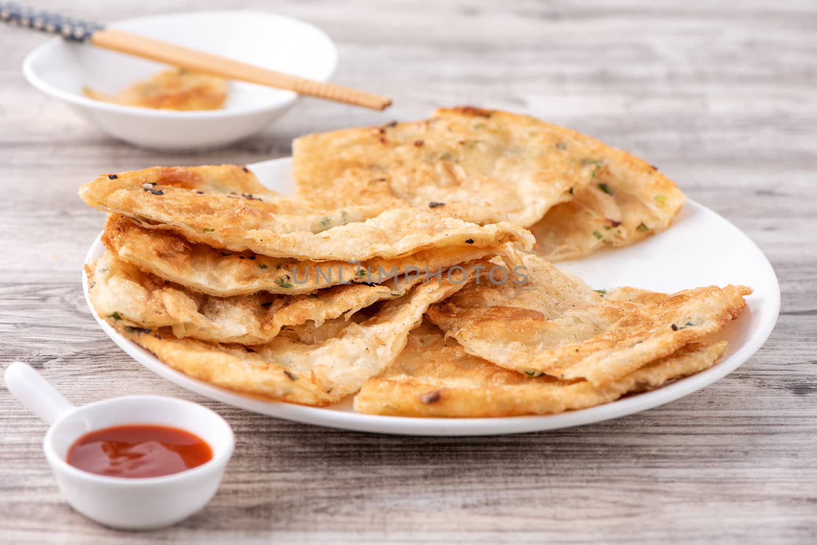 Taiwanese food - delicious flaky scallion pie pancakes on bright wooden table background, traditional snack in Taiwan, close up.