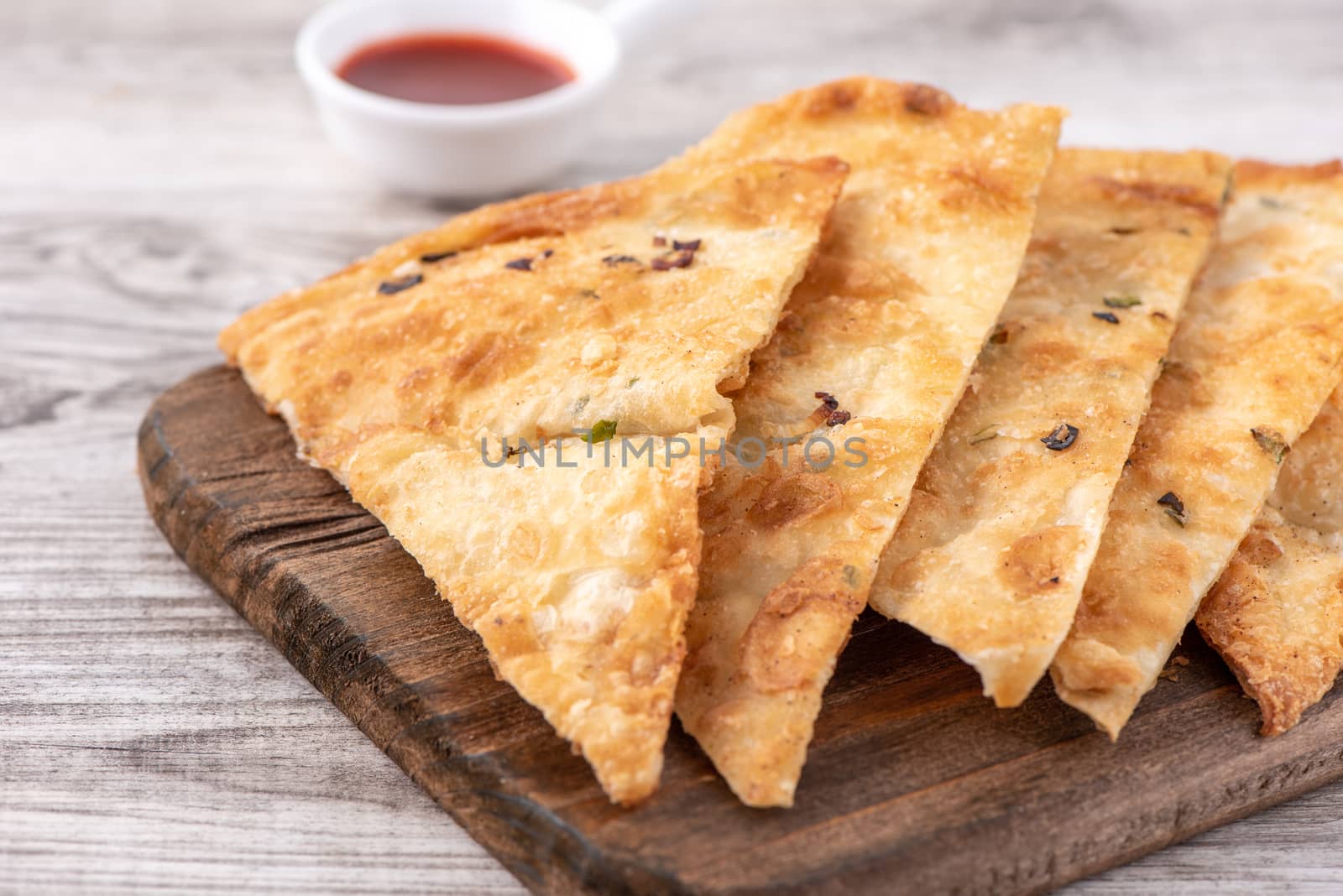 Taiwanese food - delicious flaky scallion pie pancakes on bright wooden table background, traditional snack in Taiwan, close up.