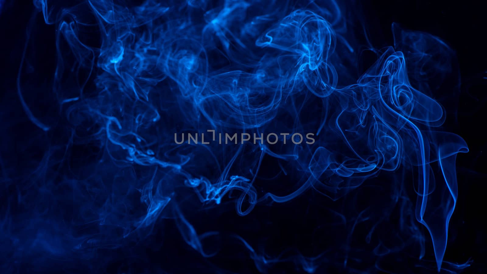 Conceptual image of blue color smoke isolated on dark black background, Halloween design element concept.