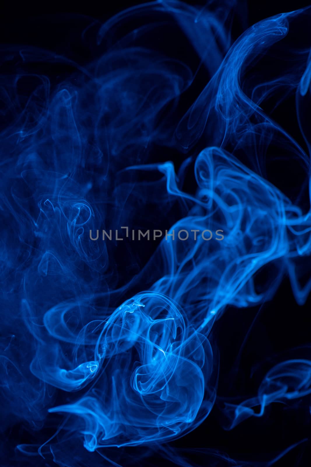 Conceptual image of blue color smoke isolated on dark black background, Halloween design element concept.