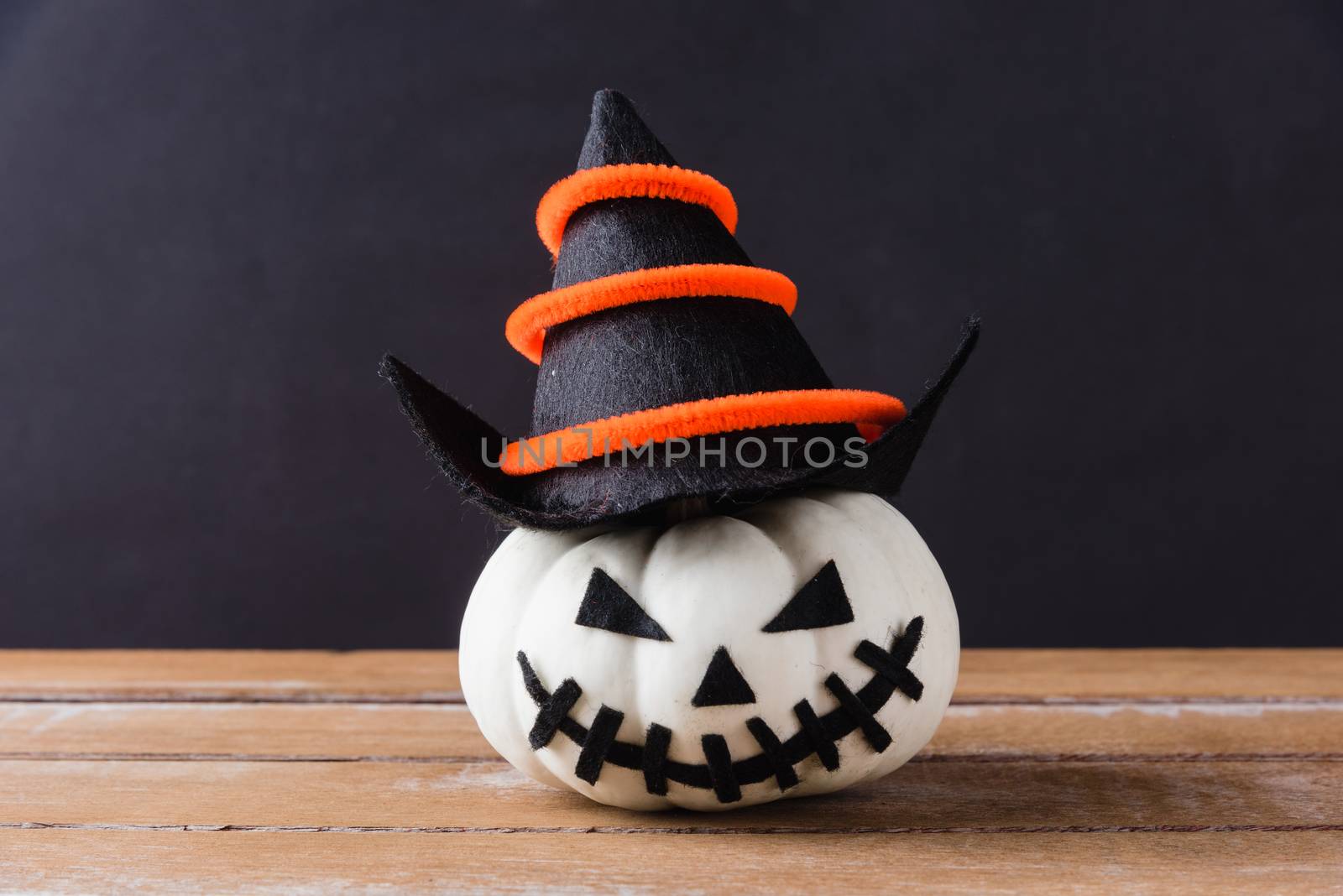 Funny Halloween day party concept ghost pumpkins head jack lantern scary smile wear hat on wooden table and black background, studio shot isolated, Holiday decoration