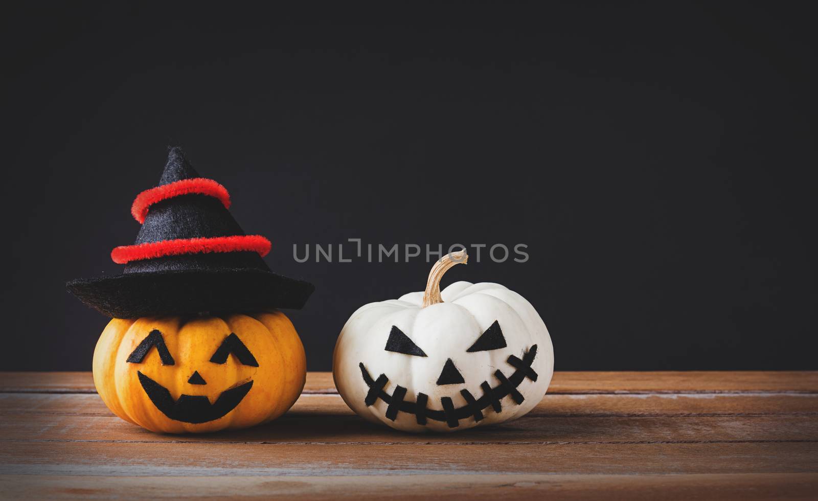 Funny Halloween day party concept ghost pumpkins head jack lantern scary smile wear hat on wooden table and black background, studio shot isolated, Holiday decoration