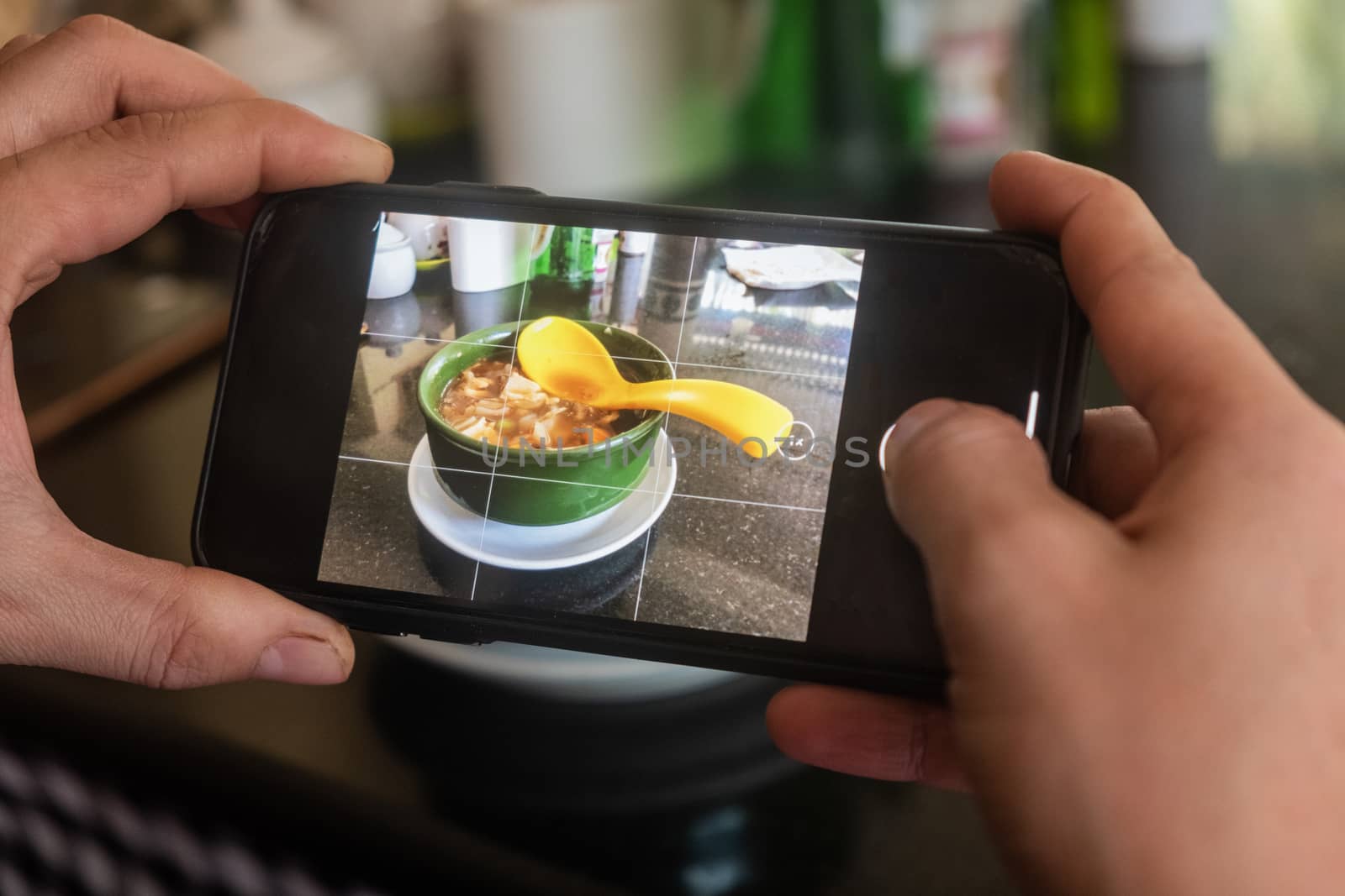 Hands of male blogger photographing mushroom soup through smart phone at a cafe