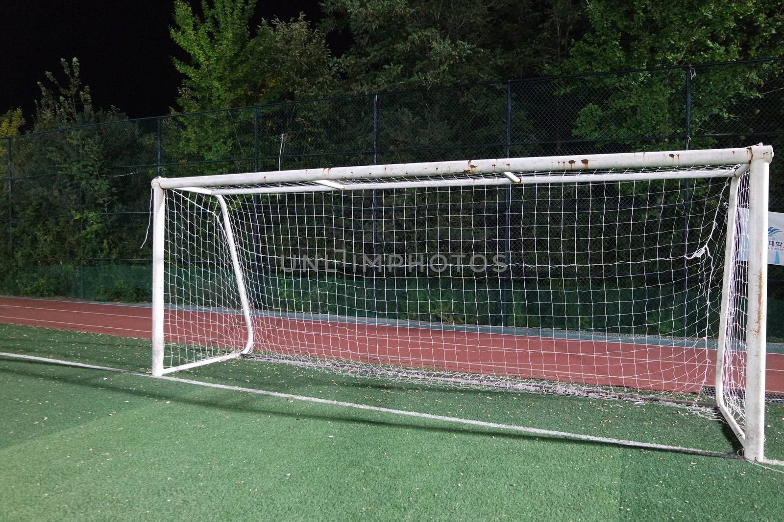 Night view of a soccer goal net under flood lights. Closeup view of goal net in a soccer playground