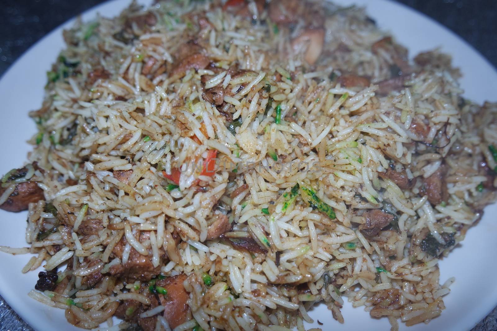 A close up view with selective focus of cooked white Basmati rice pulao or biryani with chicken meat