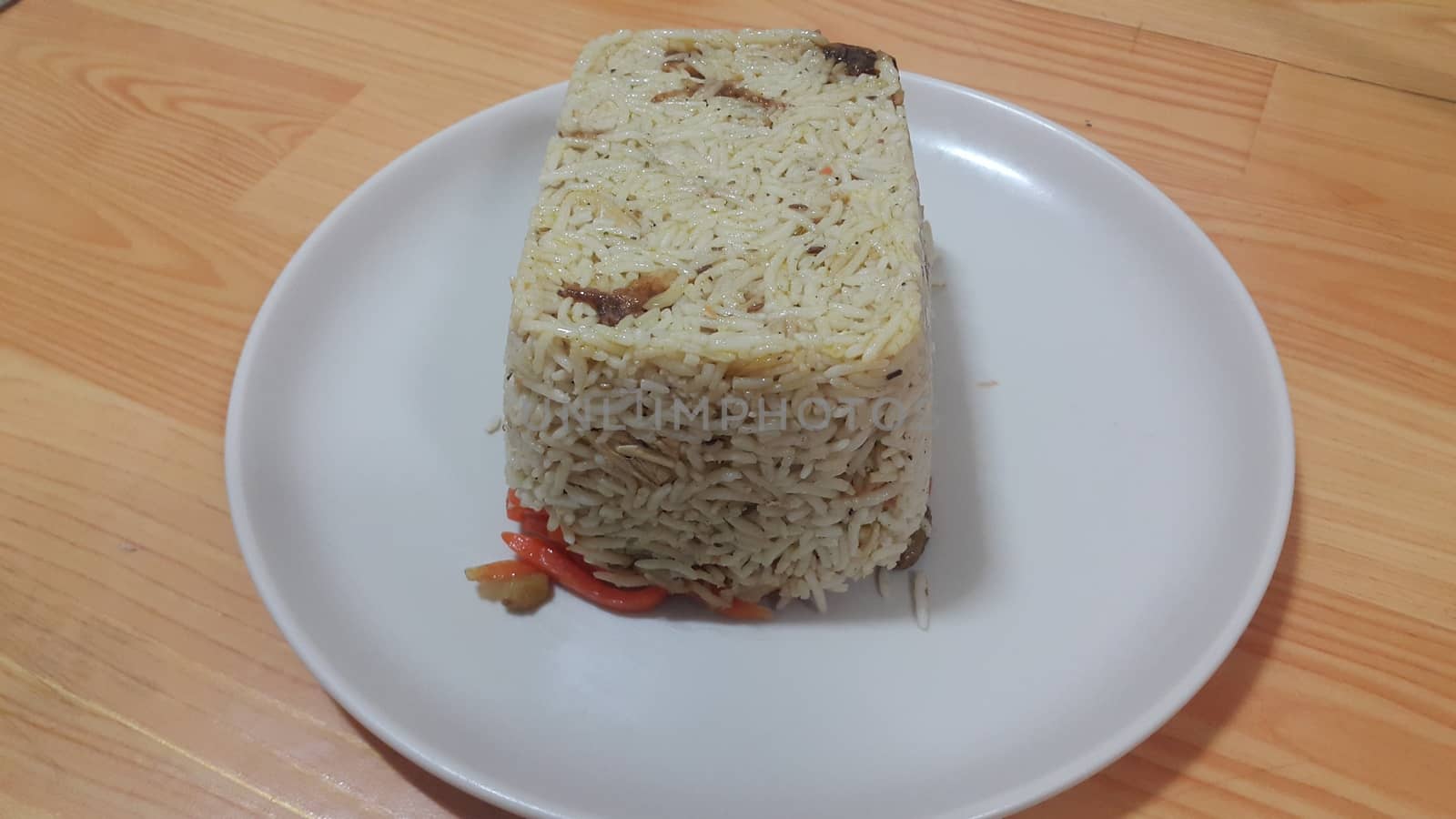 Closeup of frozen white rice cake in a white plate over wooden floor. Healthy food concept.