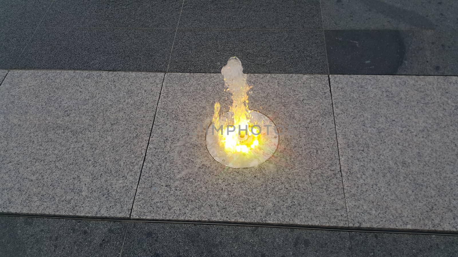 Beautiful and colorful light water fountain over concrete floor. Colorful water shape on fountain with grey background.