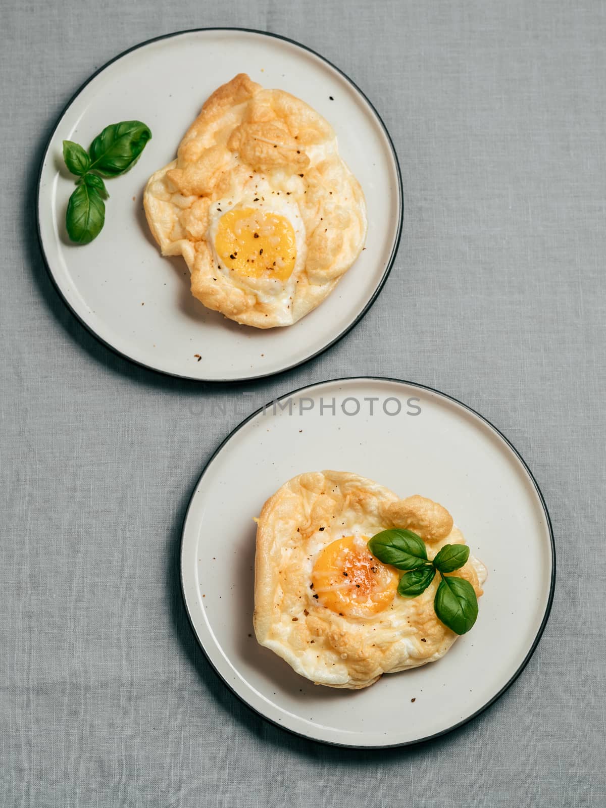 Fluffy Cloud Eggs. Trendy food - oven bake scrambled eggs with whipped egg white and whole yolk on plate Vertical.