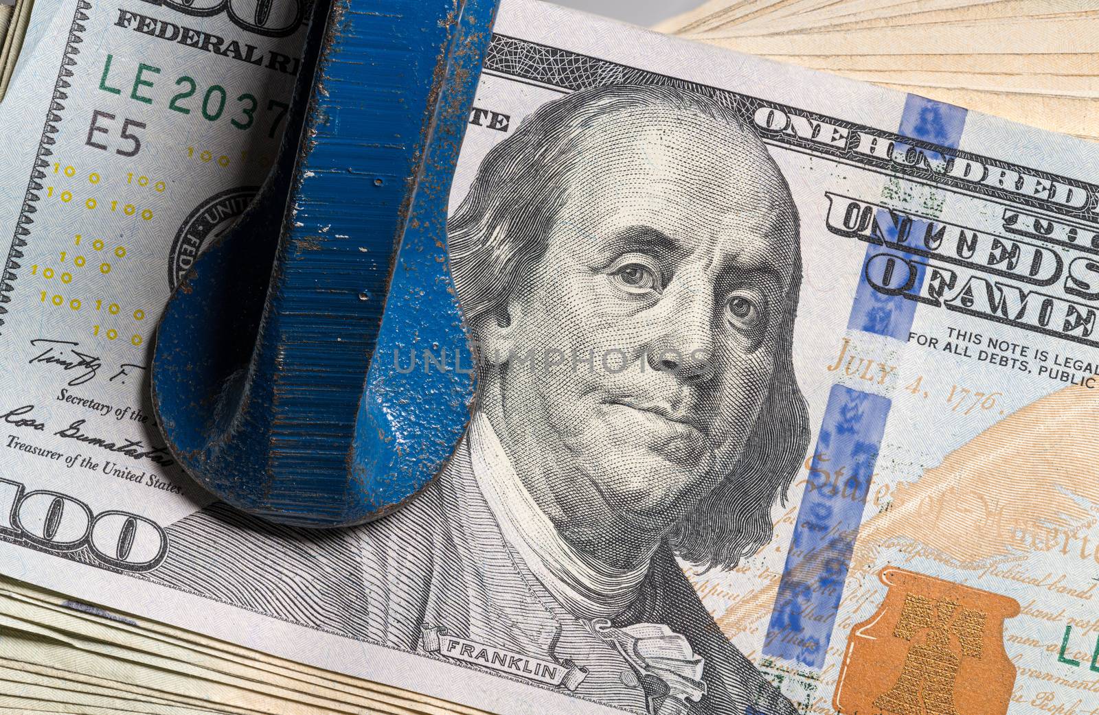 Concept for financial stress or recession. USA 100 dollar bills being squeezed between the jaws of a large vise or vice in detailed macro shot