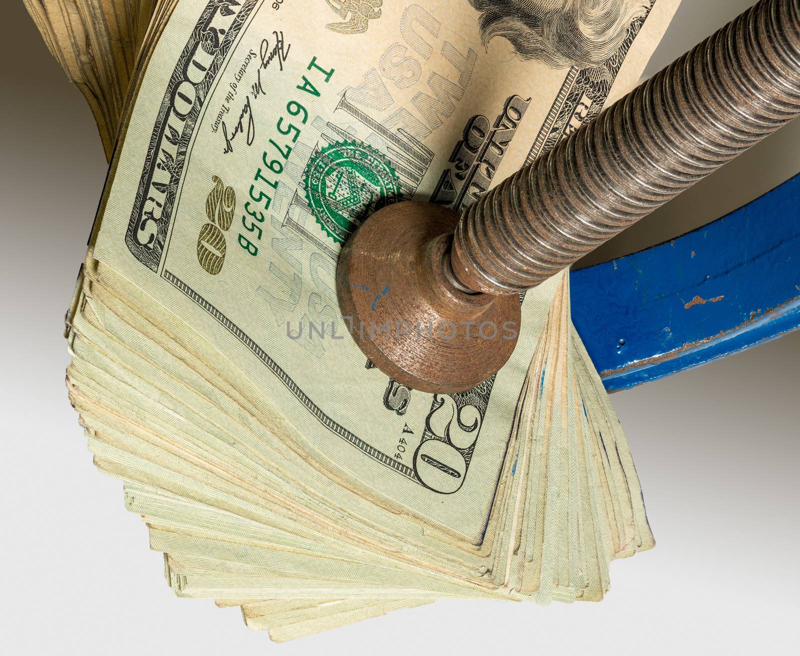 Concept for financial stress or recession. USA twenty dollar bills being squeezed between the jaws of a large vise or vice in detailed macro shot