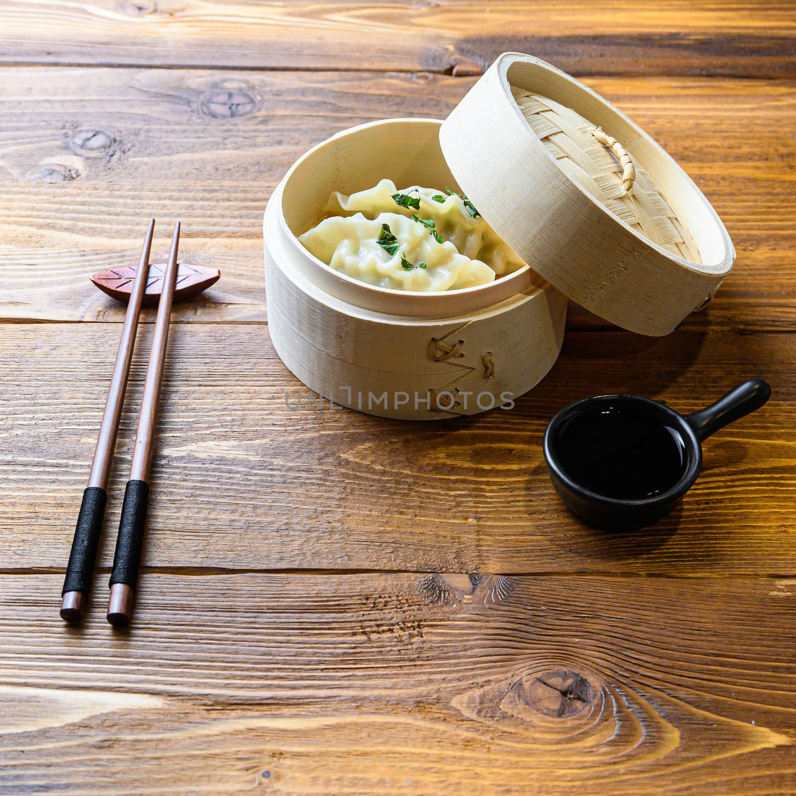 Japanese gyoza or dumplings snack with soy sauce in wooden steamer on wood japan table side view
