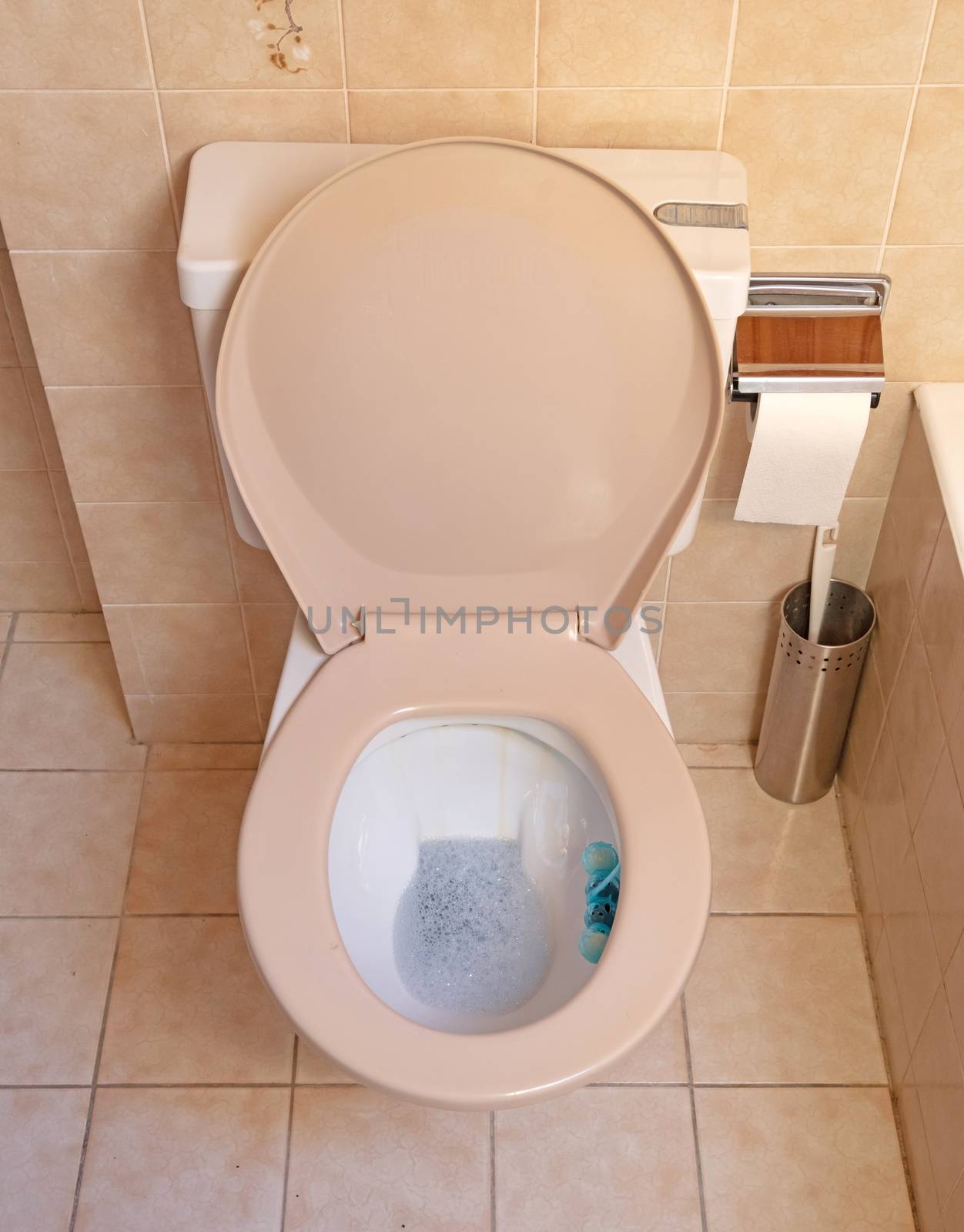 Very old toilet in a brown bathroom, empty