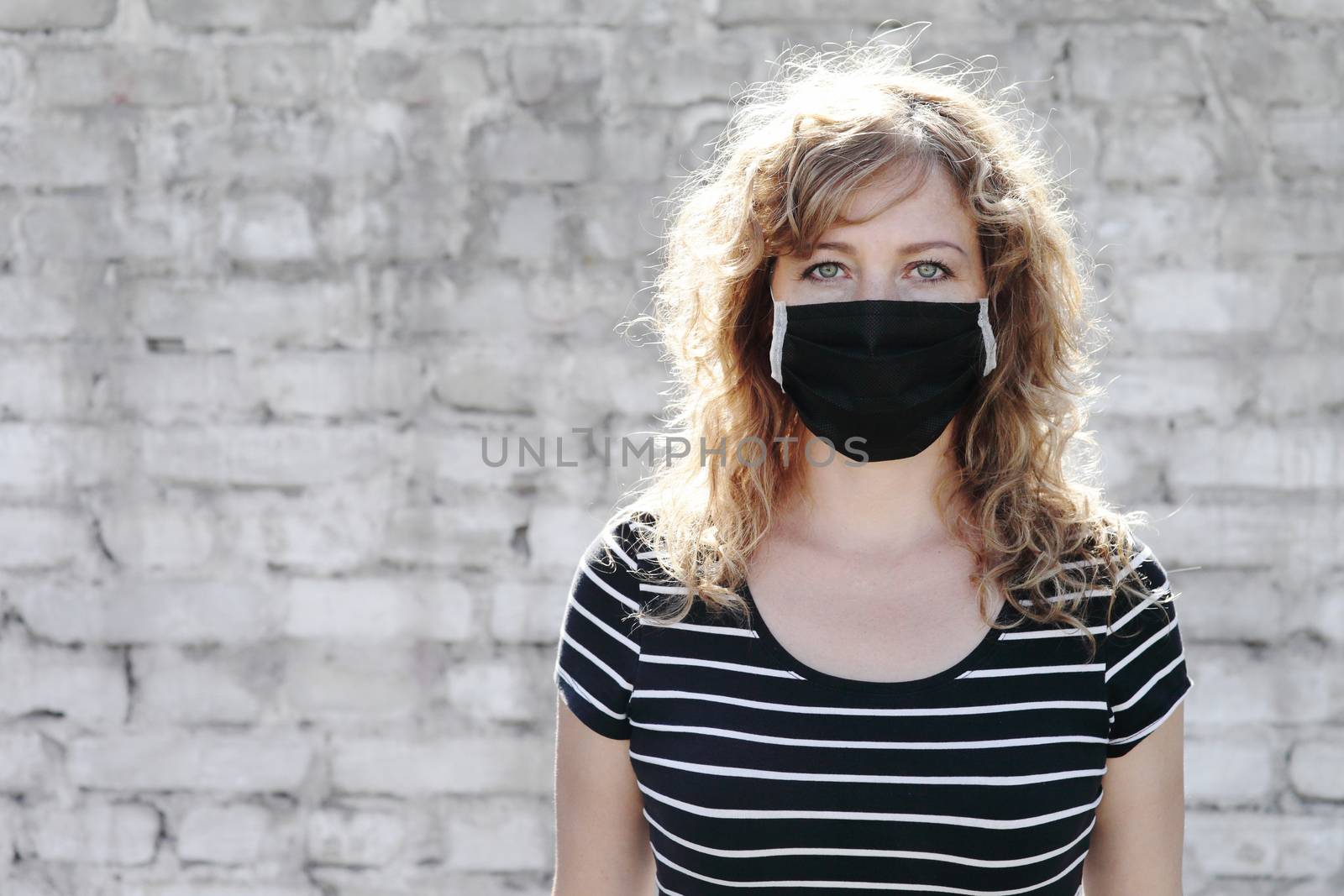 Portrait of a Girl in a protective mask free space for an inscription. Social distancing. White brick wall in the background. 