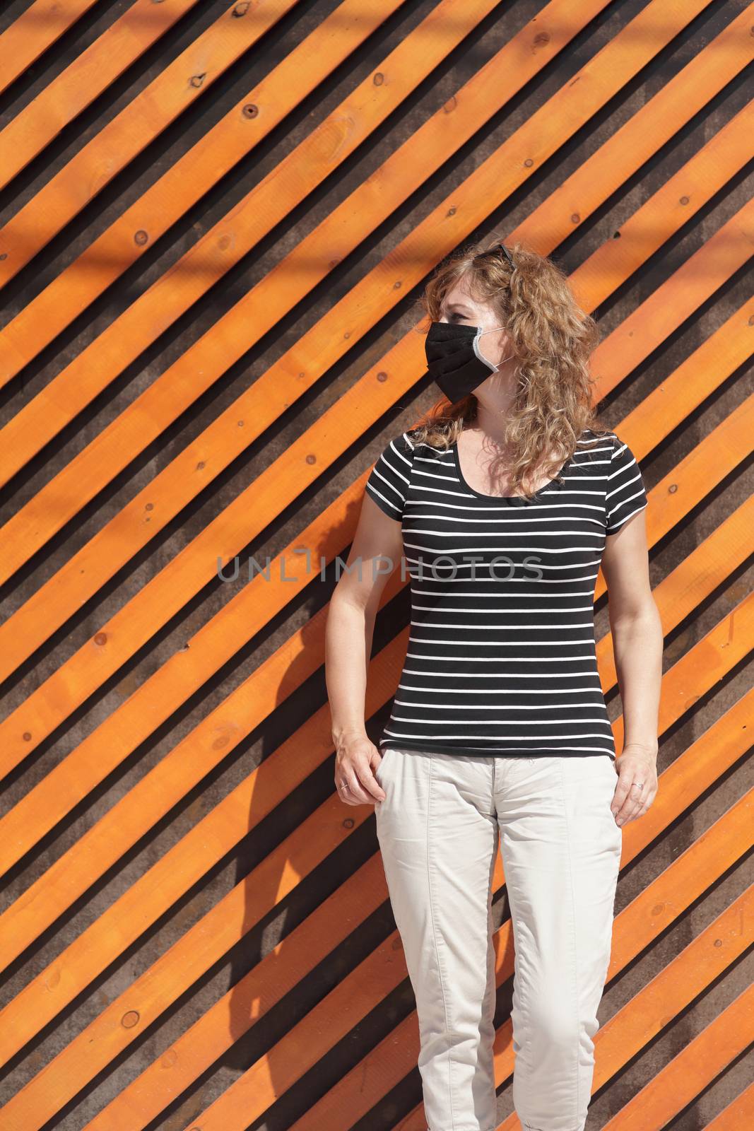 Portrait of a Girl in a protective mask free space for an inscription. Social distancing. Orange wooden wall in the background