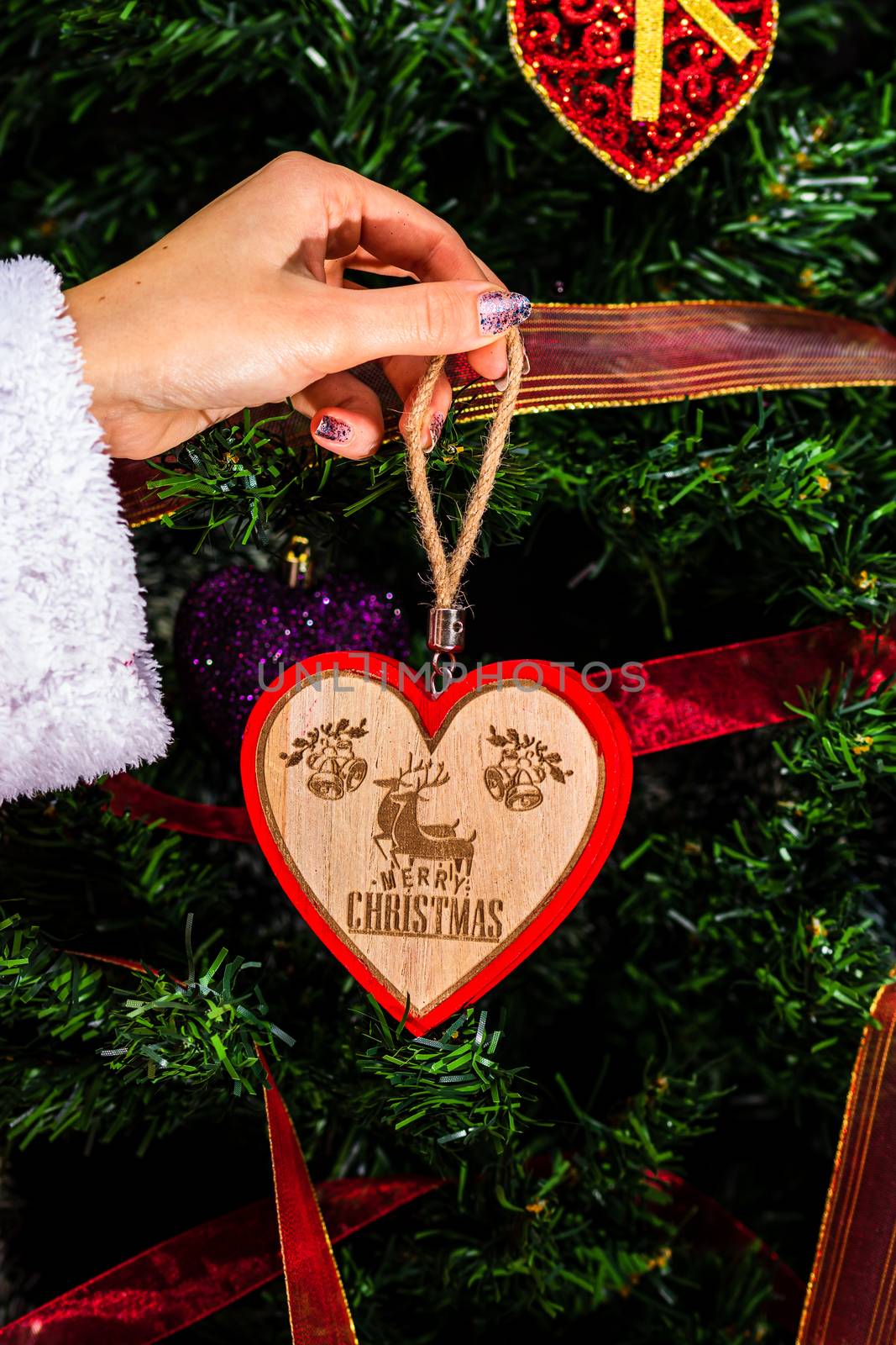 Decorating Christmas tree, hand putting Christmas decorations on by vladispas