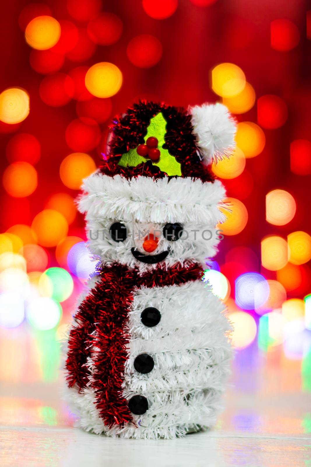 Snowman Christmas figurine near glittery gifts isolated on blurred background of lights. Christmas decorations isolated