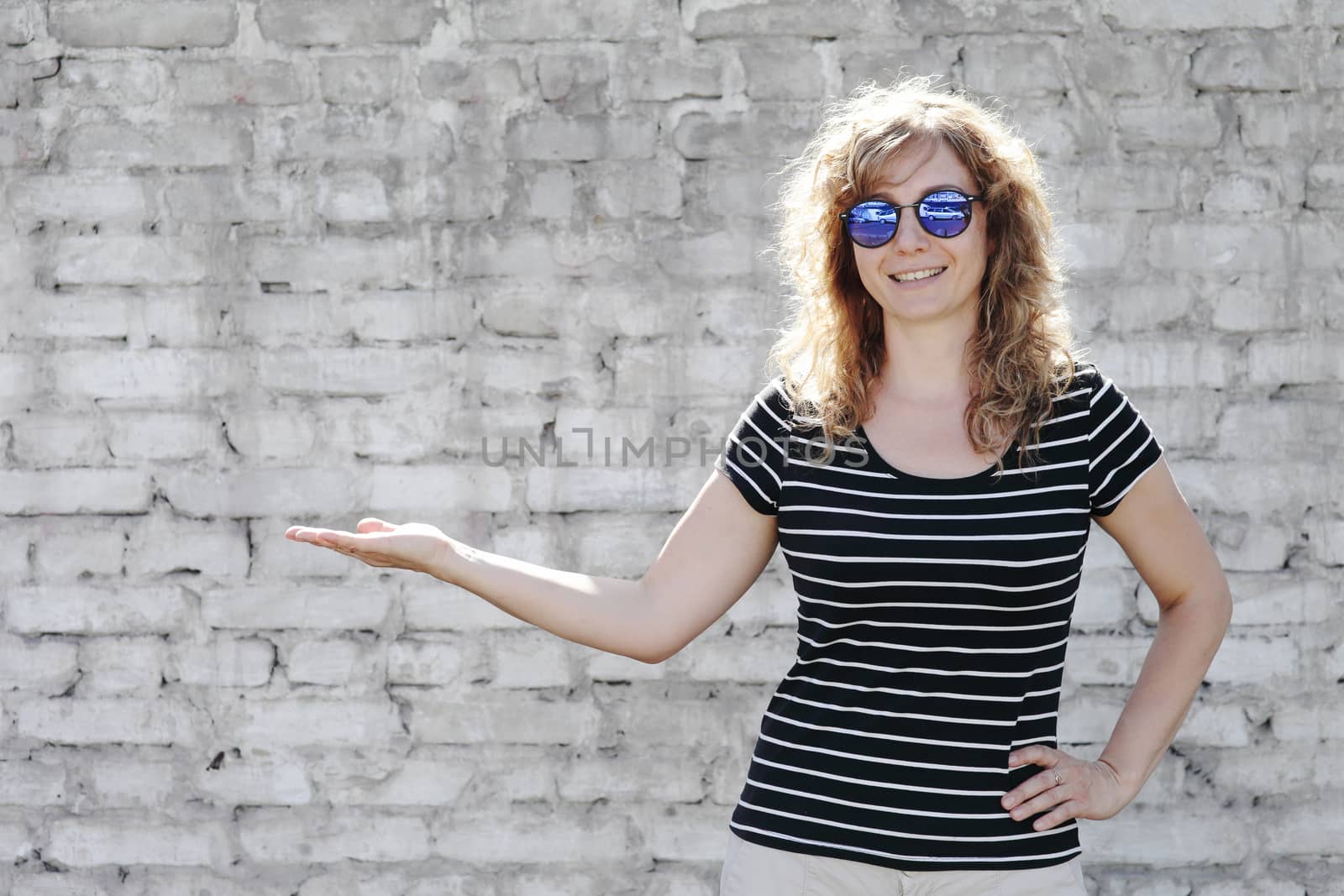Woman portrait in sunglasses, free space for inscription. White brick wall in the background