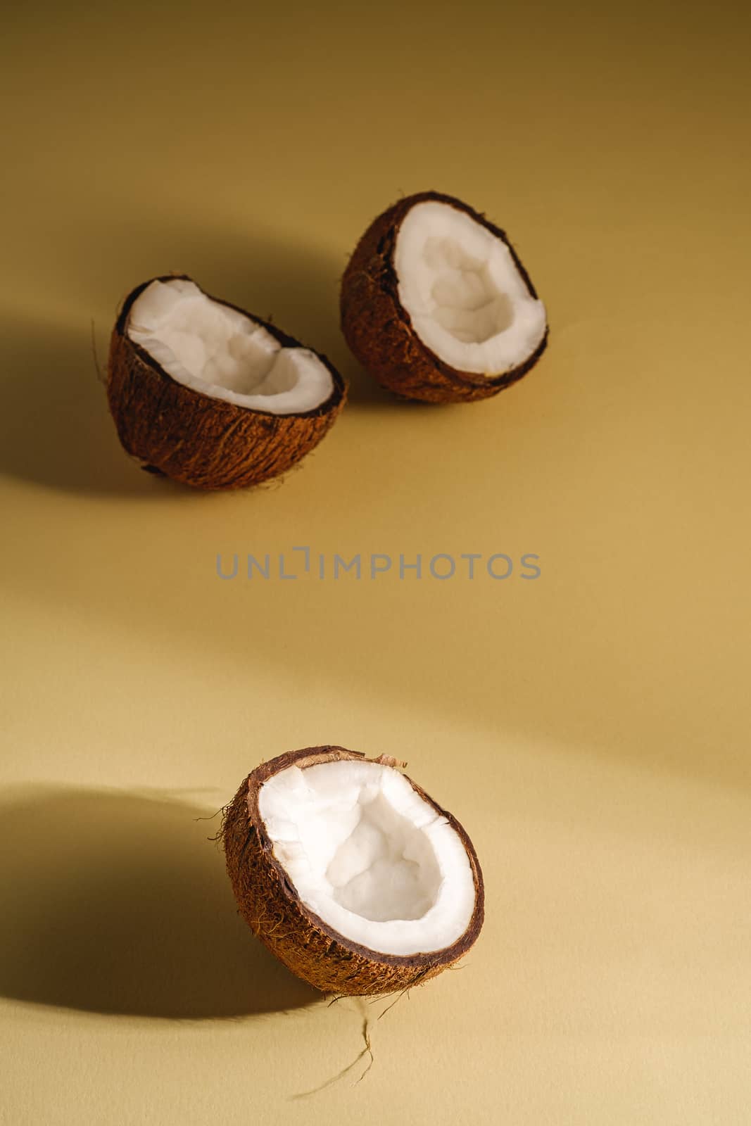 Coconut fruits on cream yellow plain background, abstract food tropical concept, angle view copy space