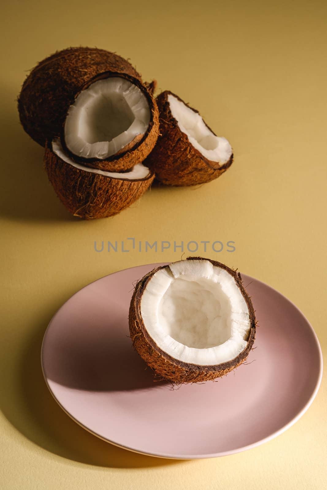 Coconut half in pink plate with nut fruits by Frostroomhead