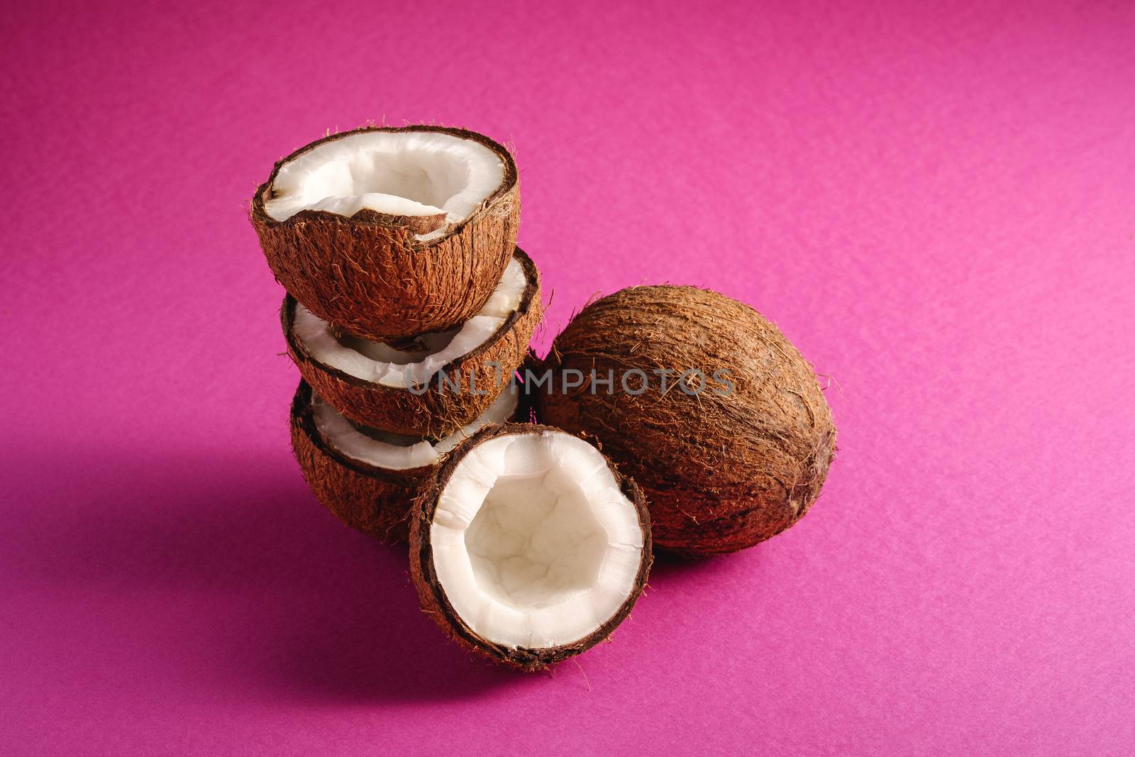 Stacked coconut fruits on pink purple plain background by Frostroomhead