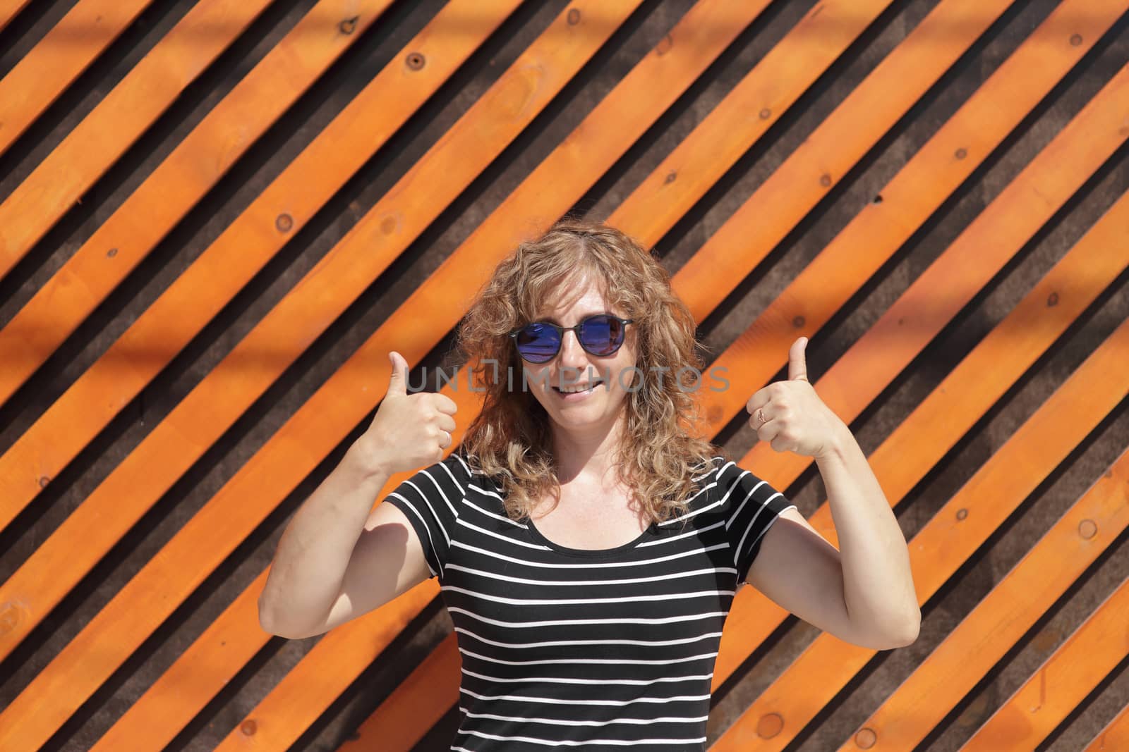 Woman portrait in sunglasses, free space for inscription. Orange wooden wall in the background