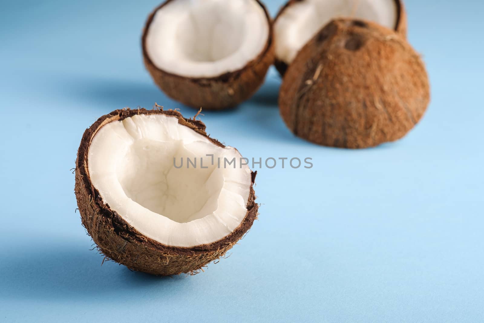 Coconut fruits on blue vibrant plain background, abstract food tropical concept, angle view macro