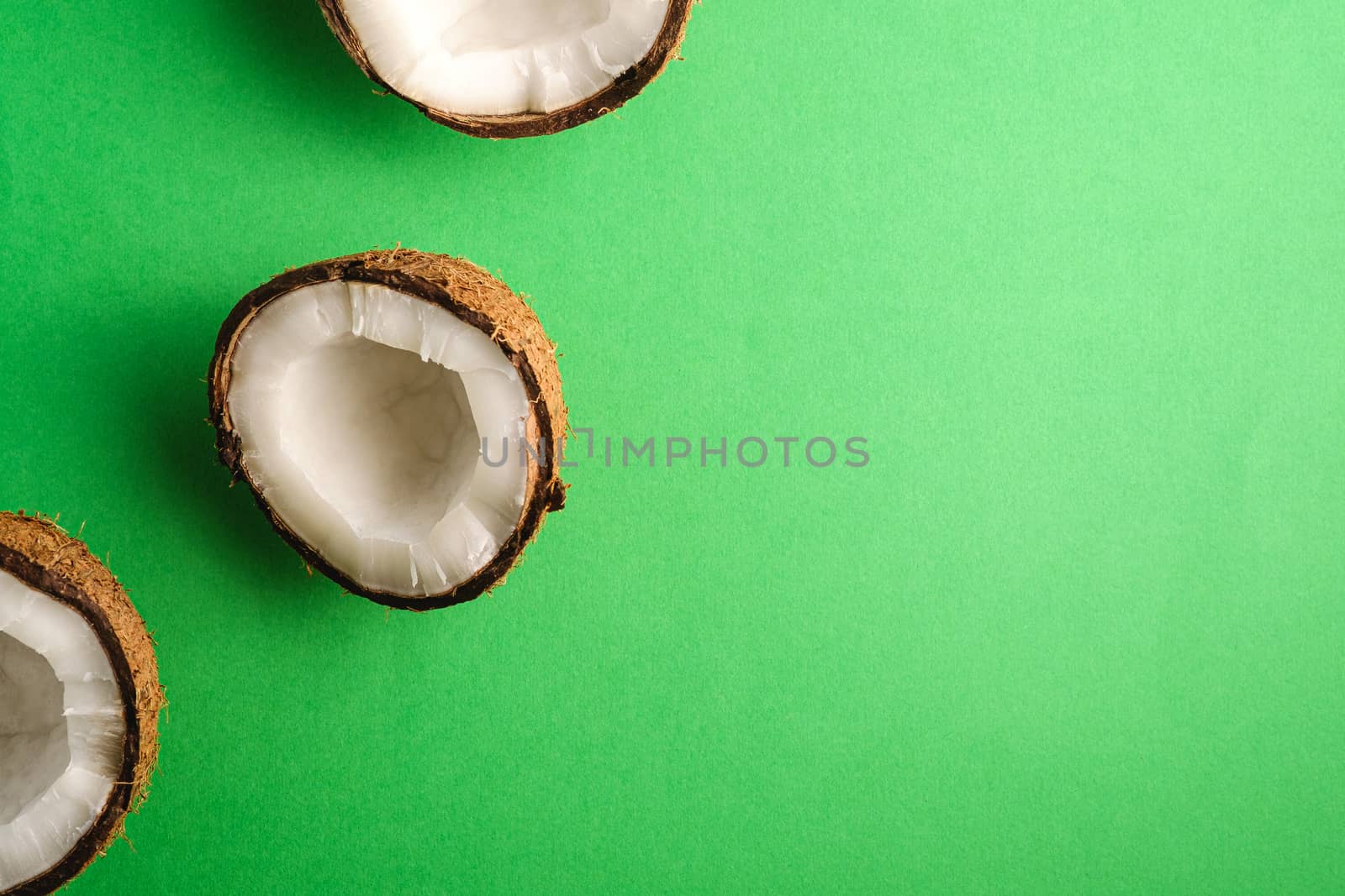 Coconut fruits on green plain background, abstract food tropical concept, top view copy space