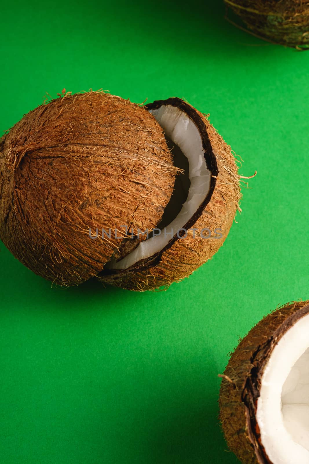 Coconut fruits on green plain background, abstract food tropical concept, angle view