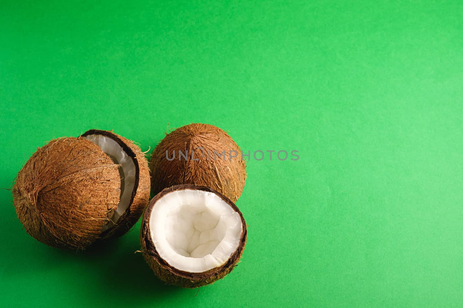 Coconut fruits on green plain background, abstract food tropical concept, angle view copy space
