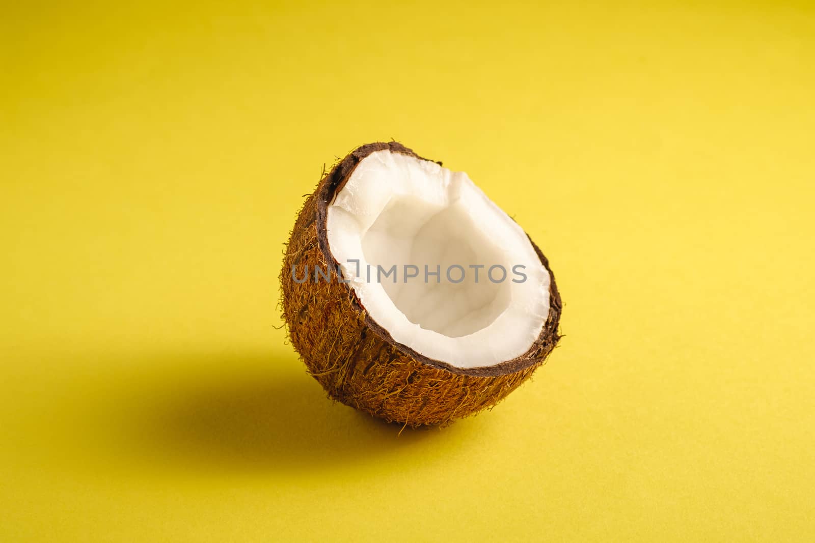 Single coconut fruit on yellow plain background, abstract food tropical concept, angle view macro