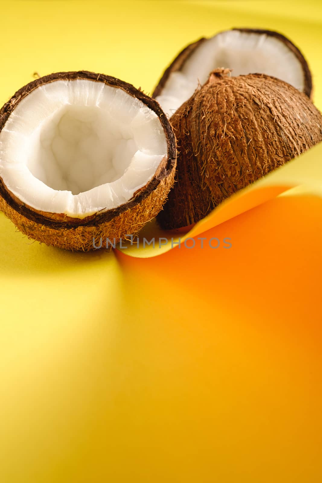 Coconut fruits on folded paper yellow plain background, abstract food tropical concept, angle view