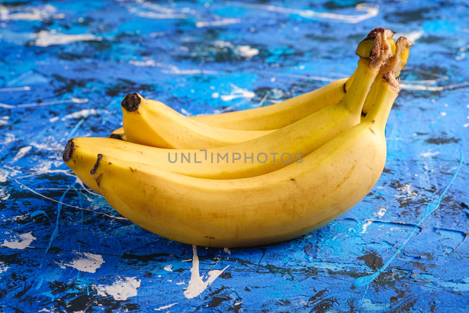 Banana fruits on blue textured background, angle view