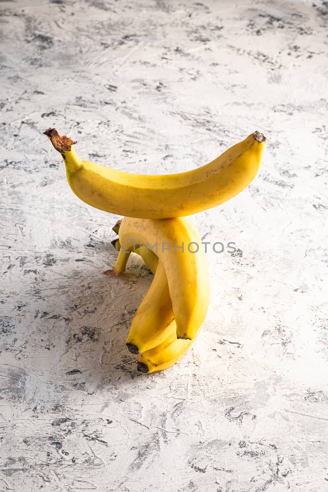 Stacked banana fruits on white textured background, angle view copy space