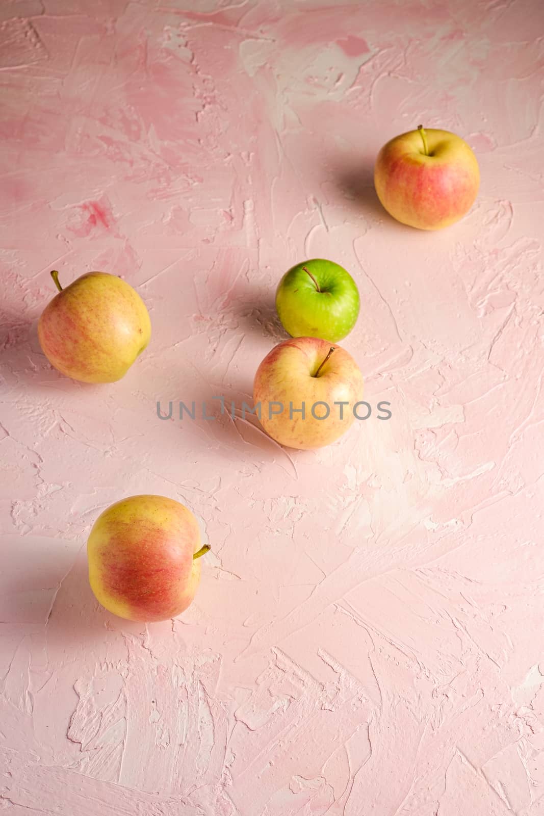 Fresh sweet apples on pink textured background, angle view