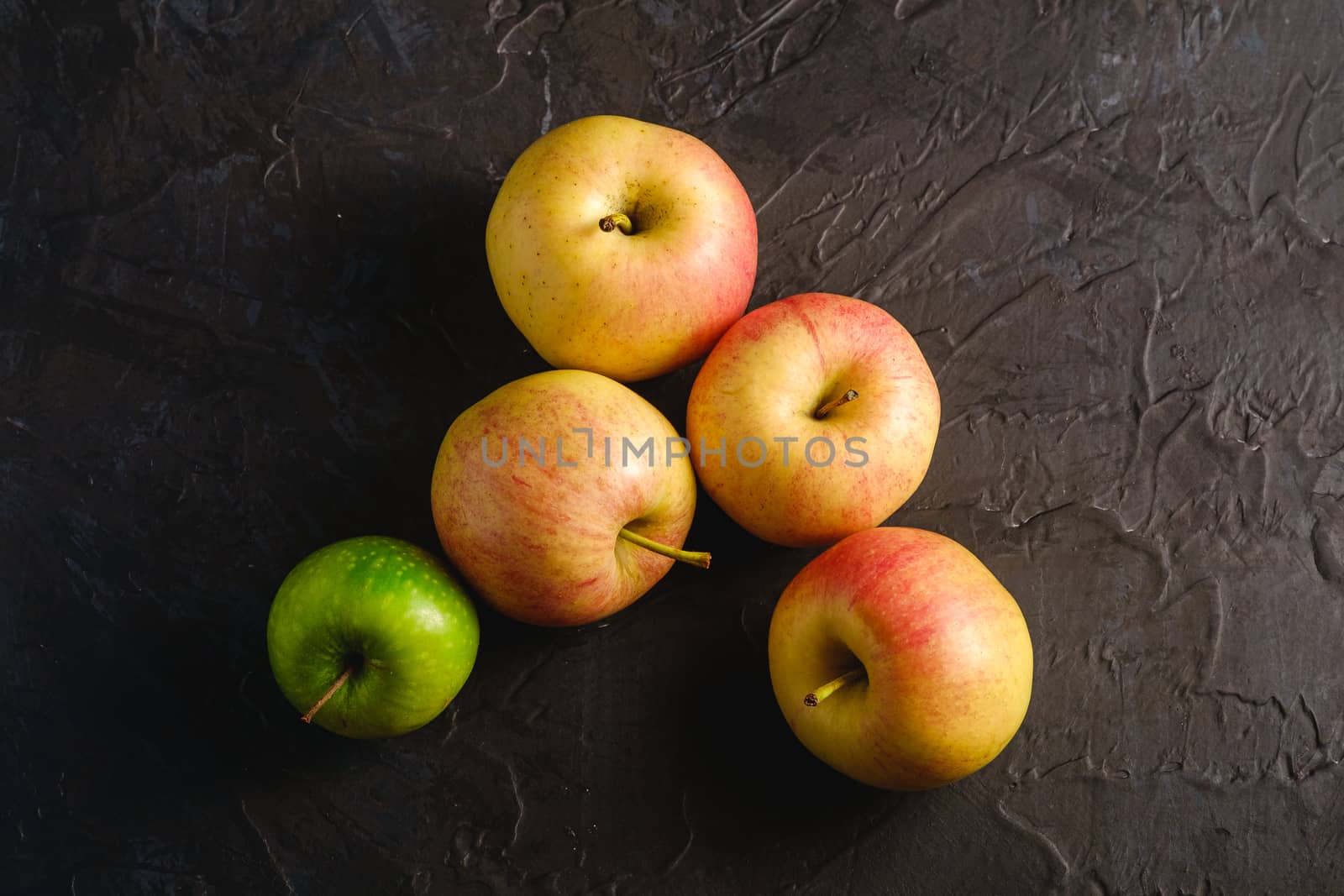 Fresh sweet apples on dark black textured background, top view