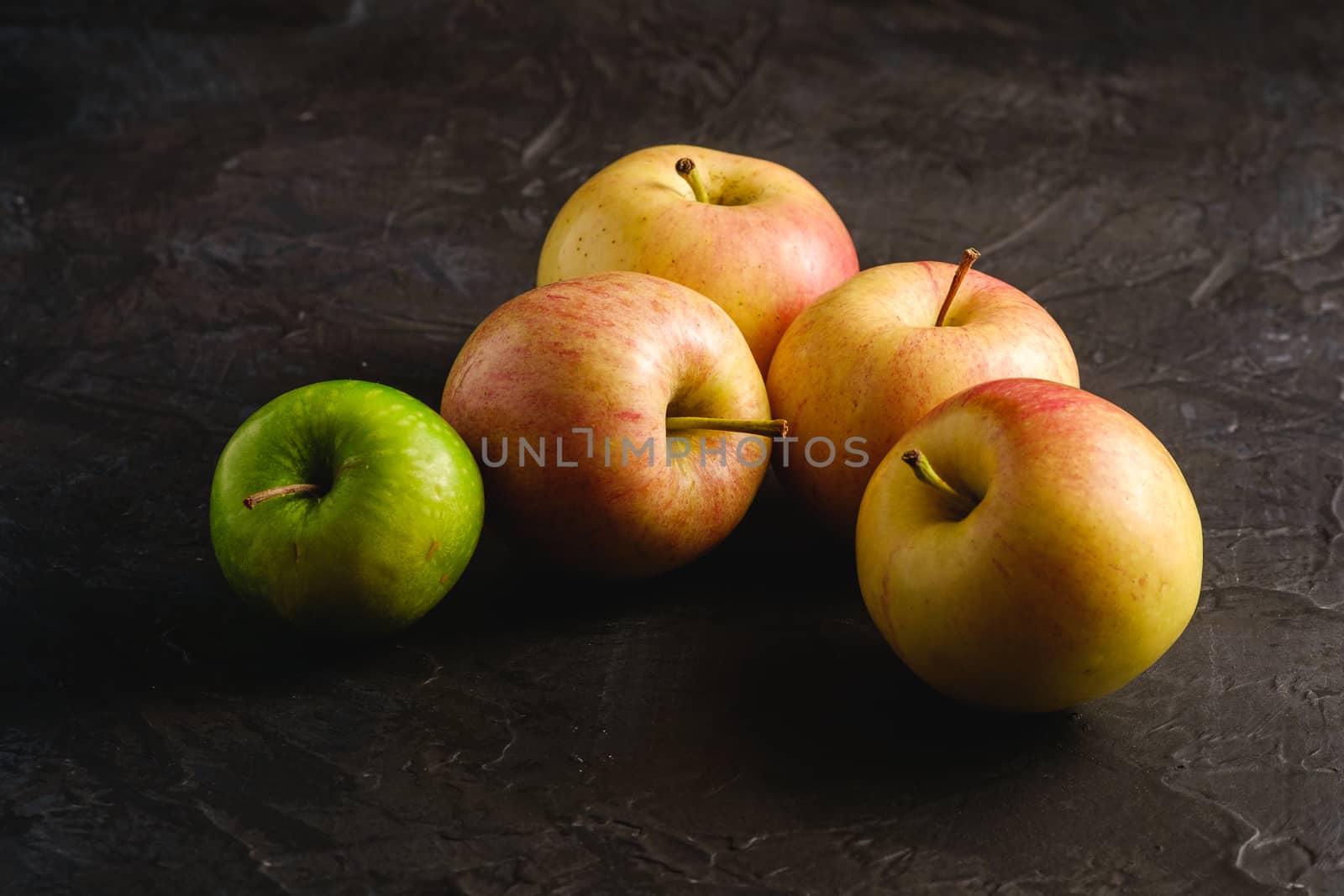 Fresh sweet apples on dark black textured background, angle view