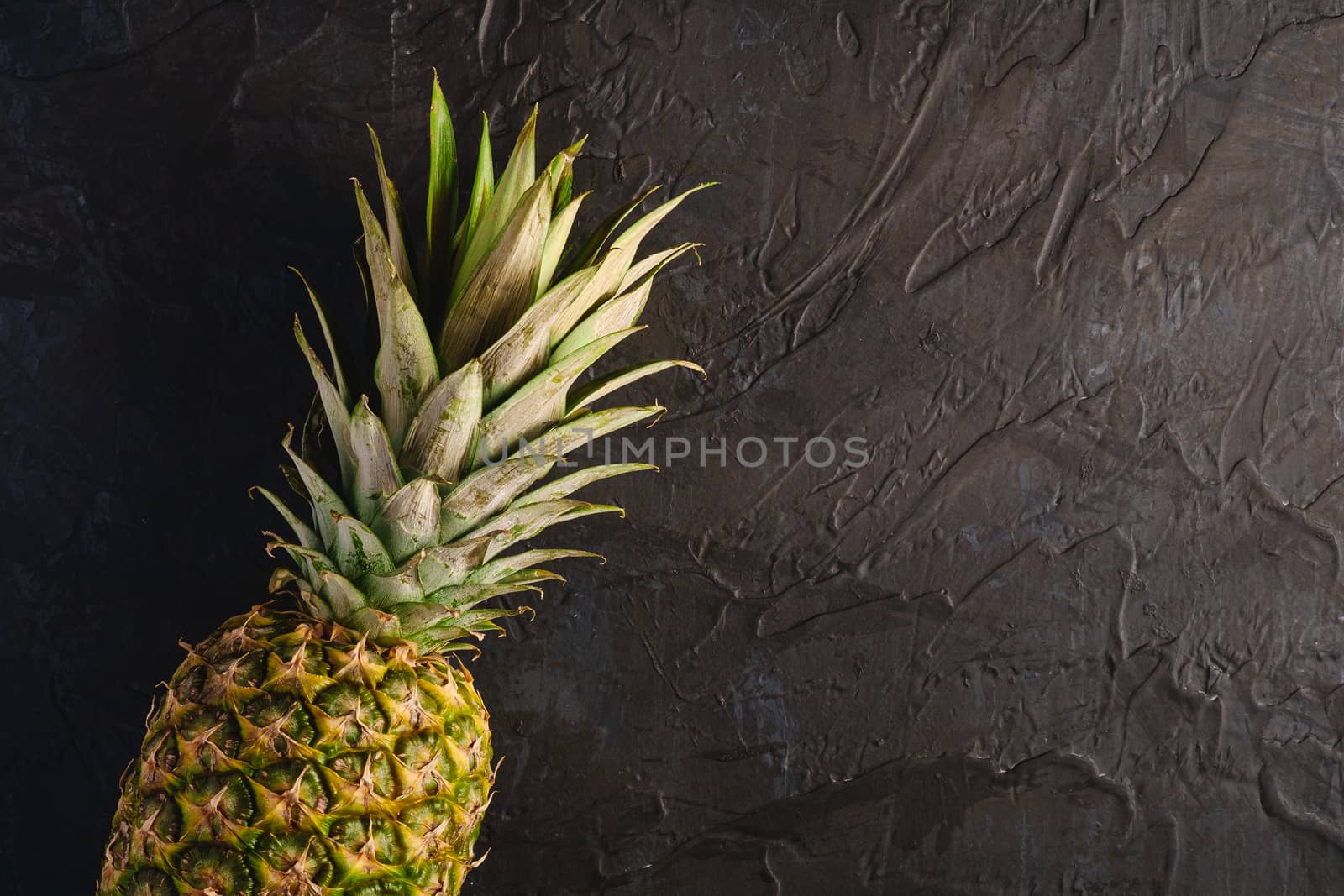 Fresh sweet pineapple on dark black textured background, top view copy space